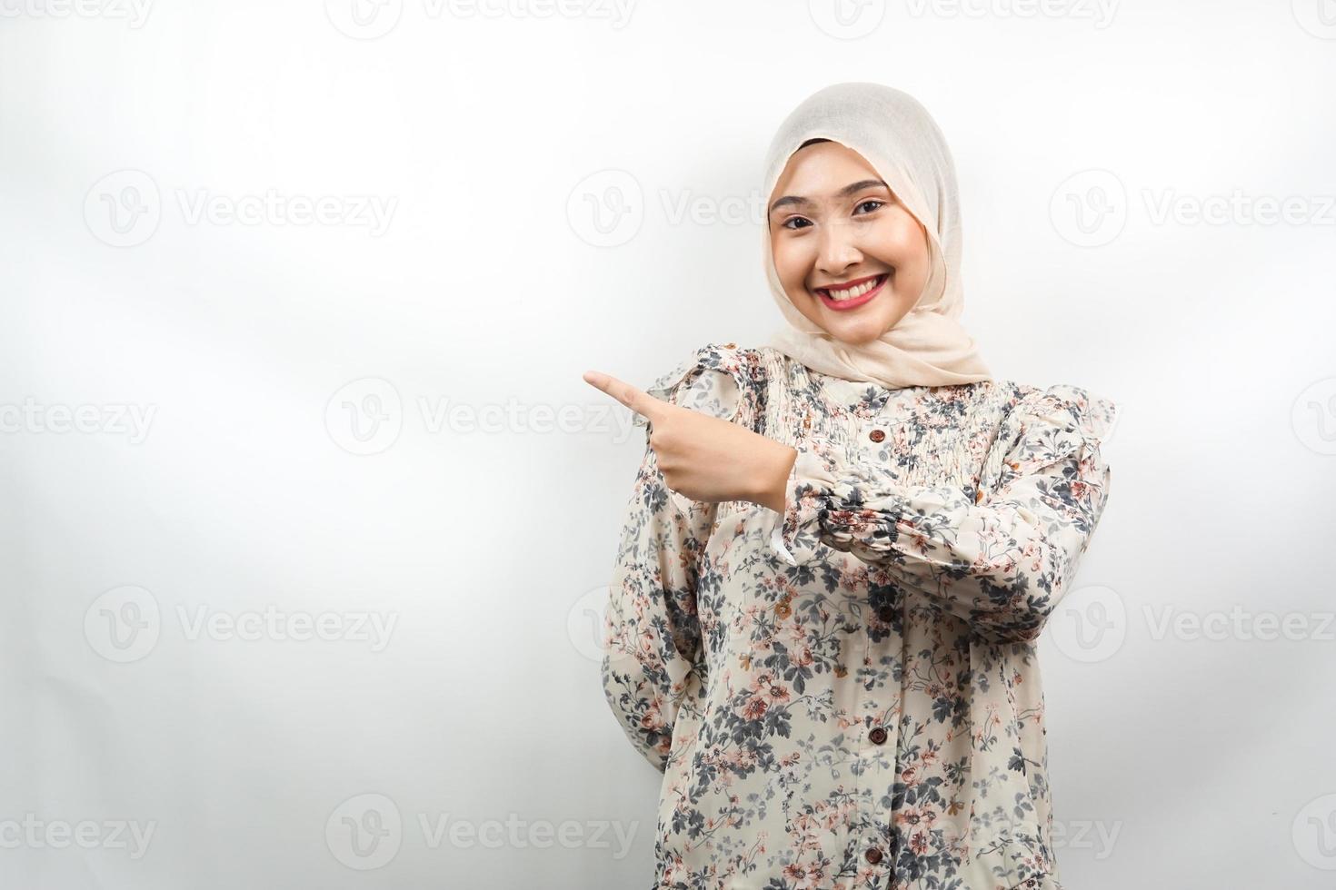 bela jovem asiática muçulmana com as mãos apontando o espaço vazio, apresentando algo, sorrindo confiante, entusiasmado, alegre, olhando para a câmera, isolado no fundo branco, conceito de publicidade foto