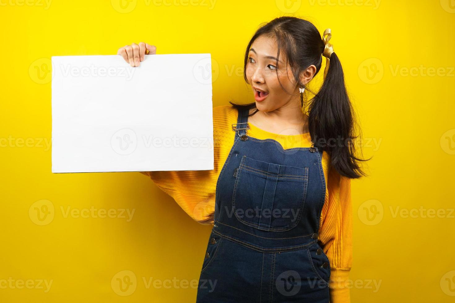 jovem bonita e fofa surpresa, chocada, uau, mão segurando uma faixa vazia em branco, cartaz, quadro branco, placa de sinalização em branco, placa de propaganda branca, apresentando algo no espaço da cópia, promoção foto