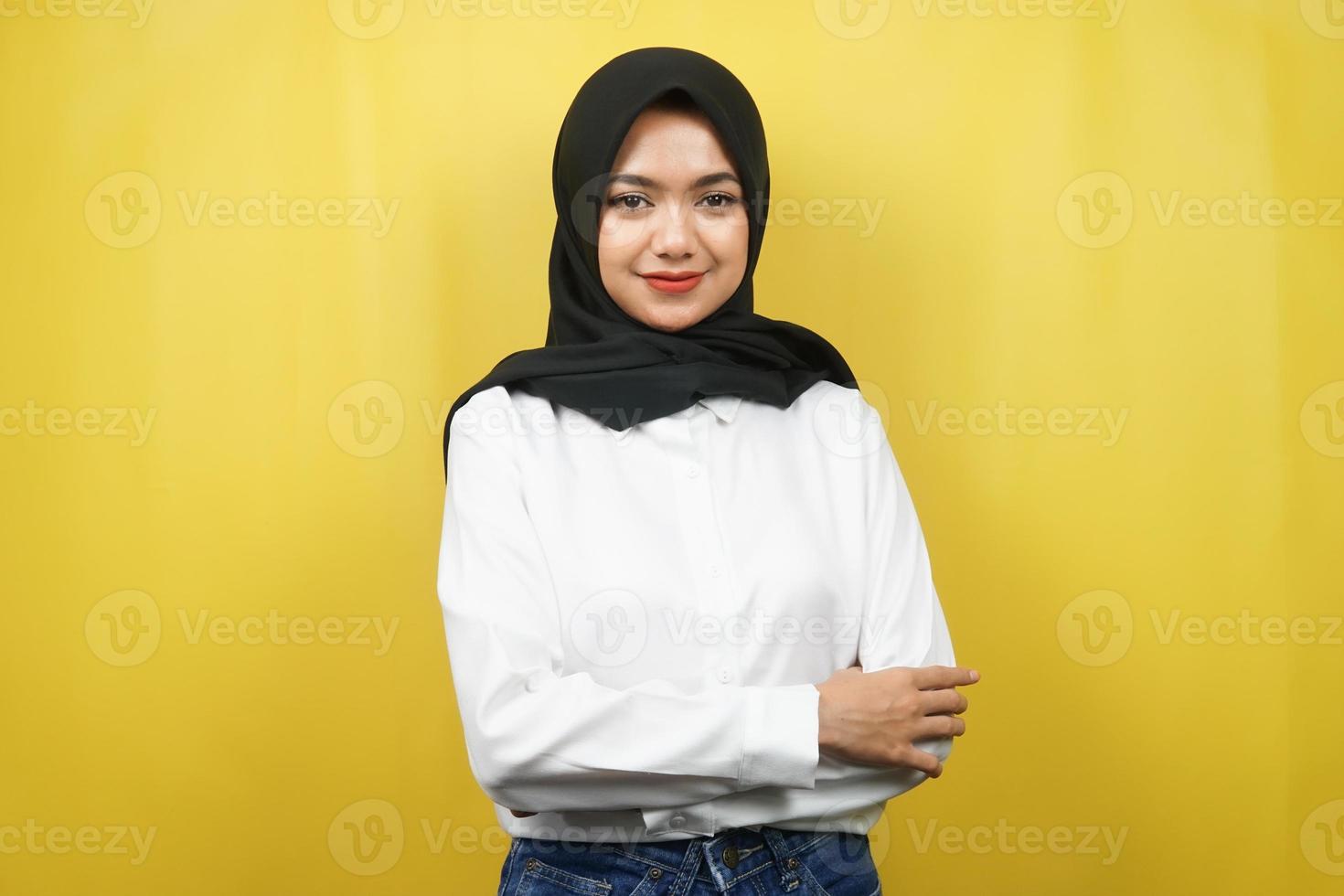 bela jovem muçulmana asiática sorrindo com confiança com os braços estendidos de frente para a câmera, isolados em um fundo amarelo foto