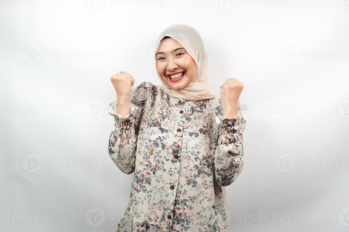 bela jovem asiática muçulmana confiante e sorridente, com o punho cerrado, socando, sinal para o espírito, luta, sinal de vitória, isolado no fundo branco foto