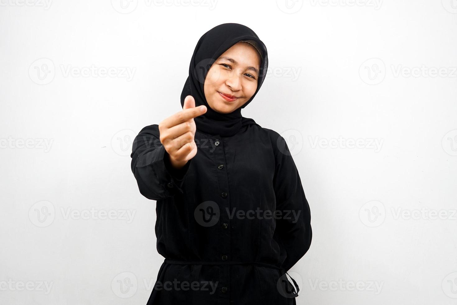 bela jovem asiática muçulmana sorrindo, com sinal de amor coreano, mão perto da câmera, isolado no fundo branco foto