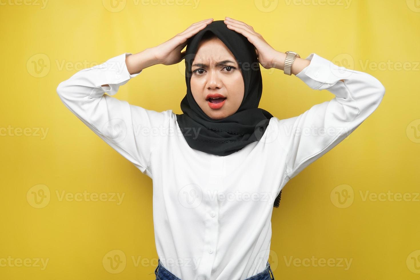 bela jovem muçulmana asiática chocada, surpresa, expressão uau, mãos segurando a cabeça, isolado no fundo amarelo foto
