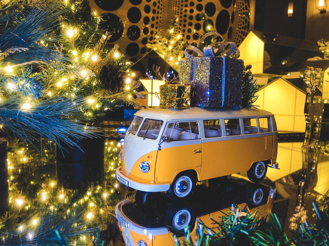 composição de natal. ônibus de brinquedo amarelo com presentes e a árvore de natal ao fundo foto