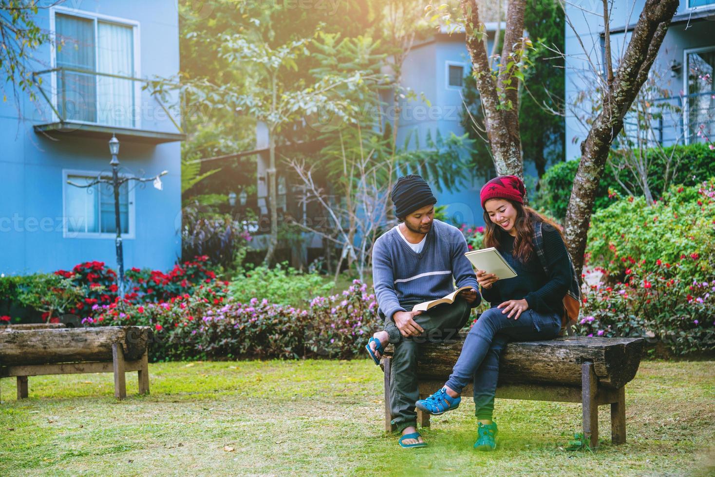 casal asiático sorriu e ficou feliz com a leitura do livro. entre os belos jardins de flores, dia dos namorados foto