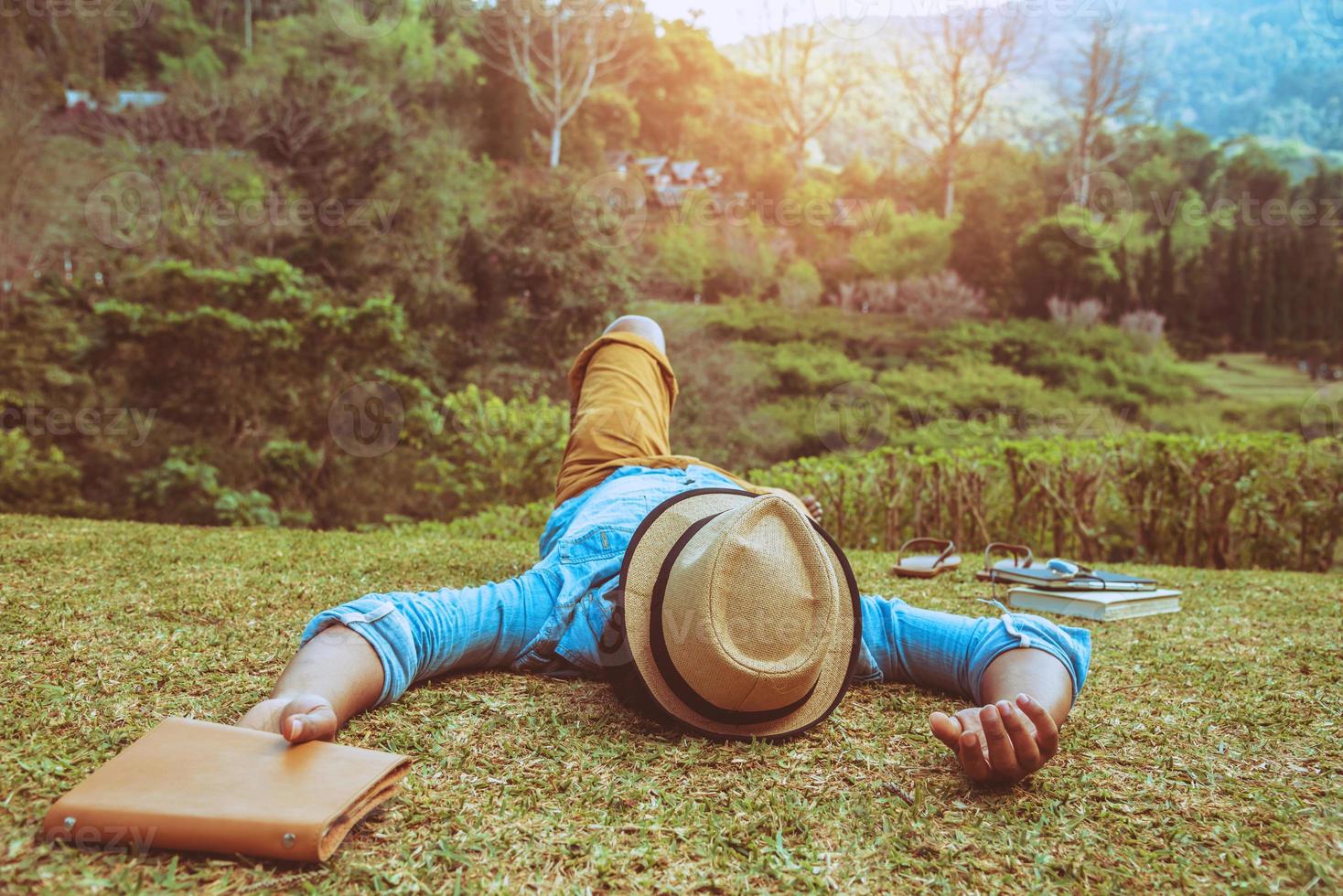 homem asiático viajar natureza. viajar relaxar. dormir no gramado do parque. no verão. foto