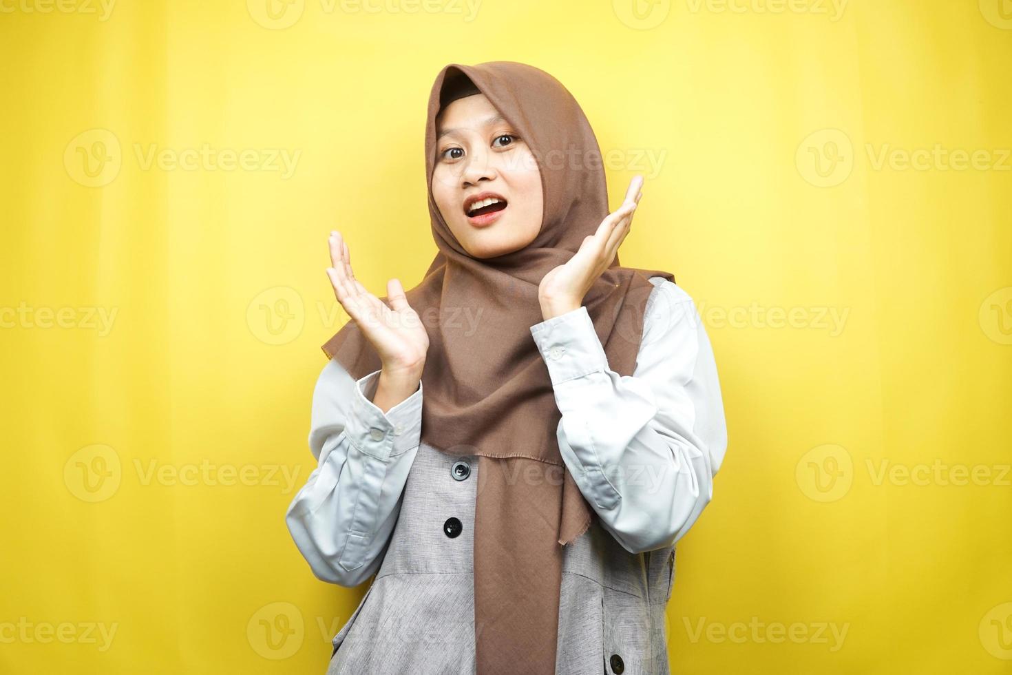 bela jovem muçulmana asiática chocada, surpresa, expressão uau, com a mão segurando a bochecha voltada para a câmera isolada no fundo amarelo foto