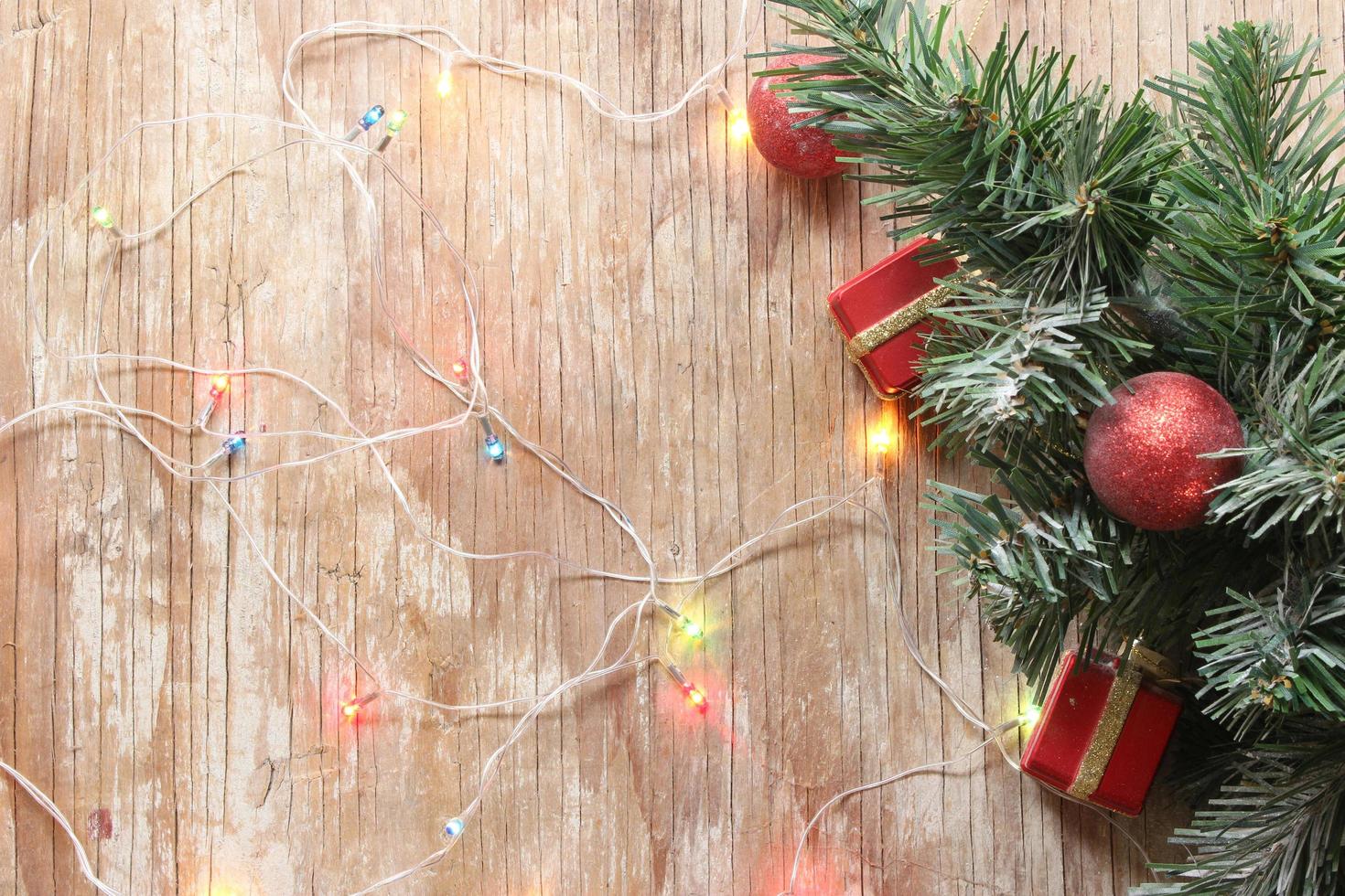 fundo da árvore de natal com enfeites e luz na placa de madeira foto