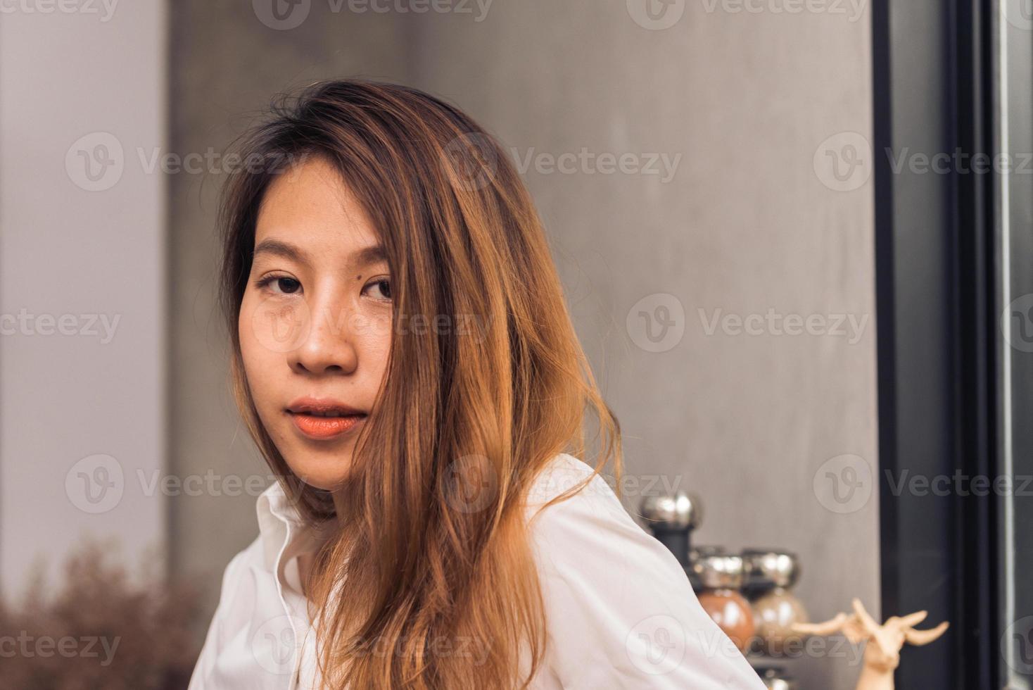 protrait da jovem mulher asiática barista dar as boas-vindas ao seu cliente ao café em uma tarde de luz quente com um lindo sorriso. jovem mulher barista sorrir em sua pequena cafeteria. conceito de comida e bebida. foto