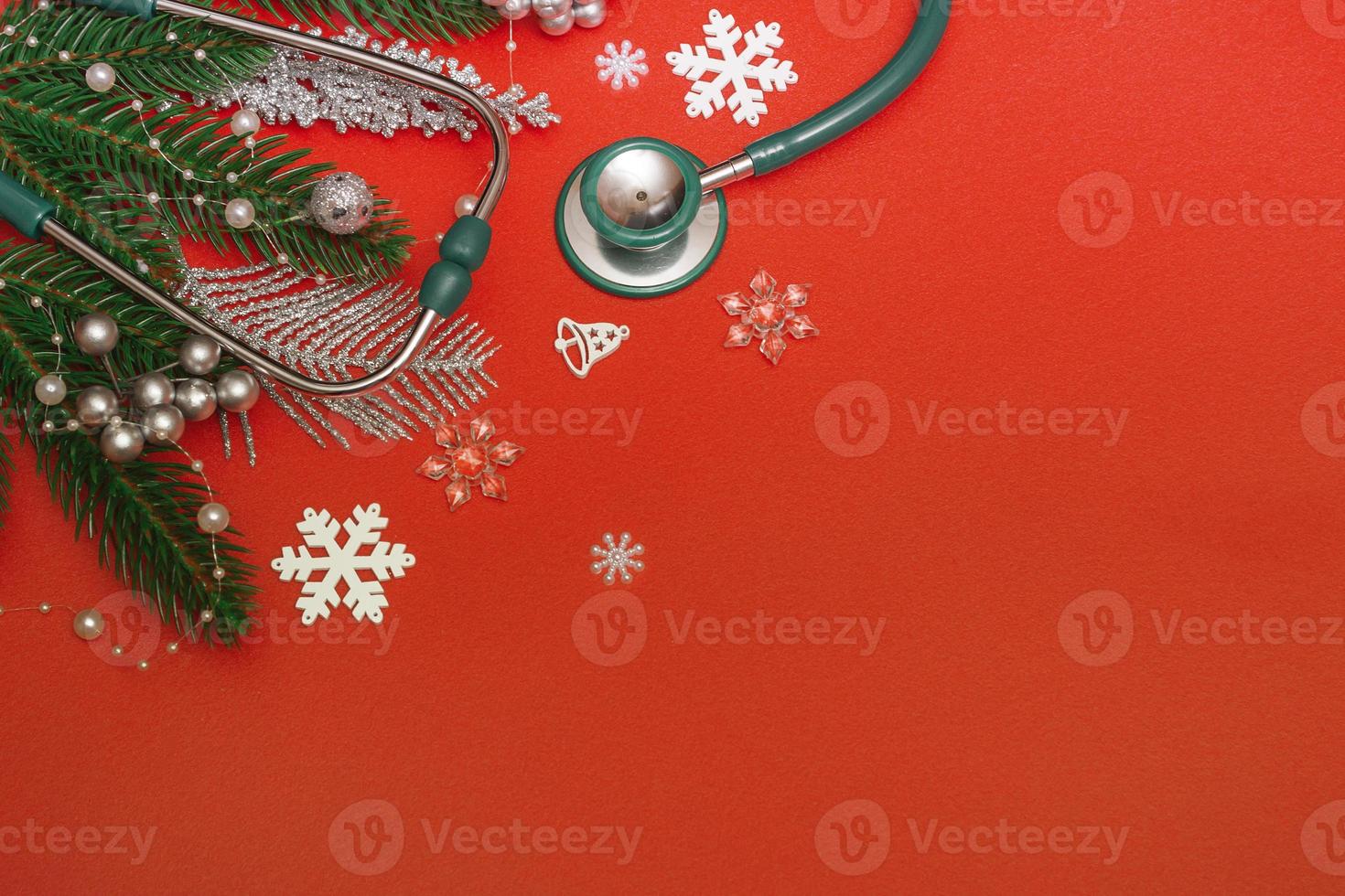 vista superior de decorações de Natal planas e estetoscópio sobre fundo vermelho. conceito de anúncio médico, banner. copie o espaço foto