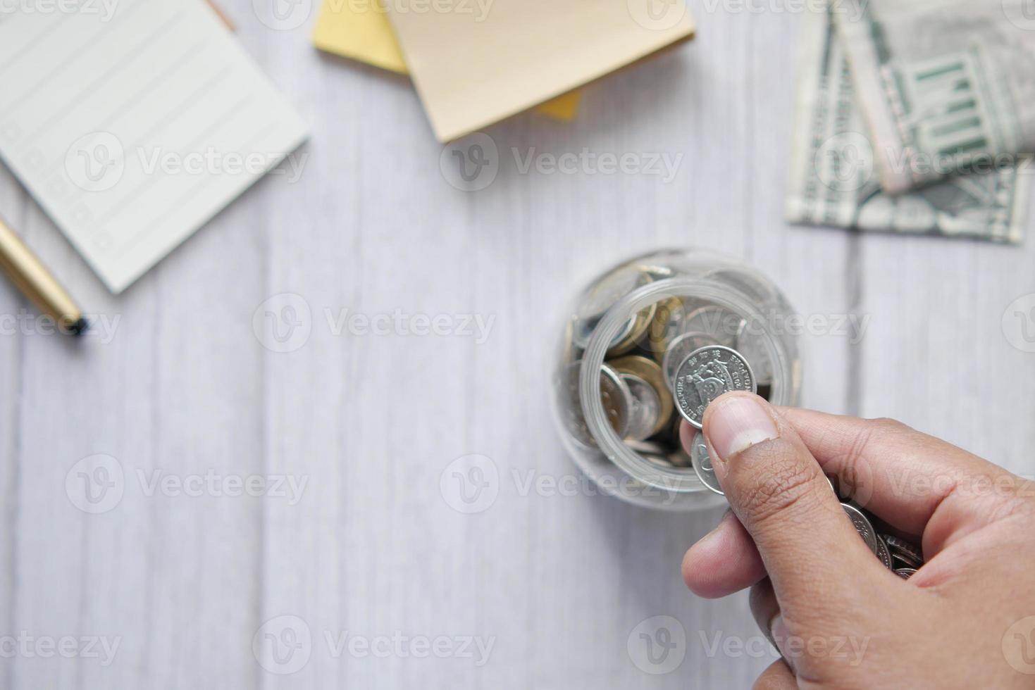 jovem guardando moedas em uma jarra branca localizada foto