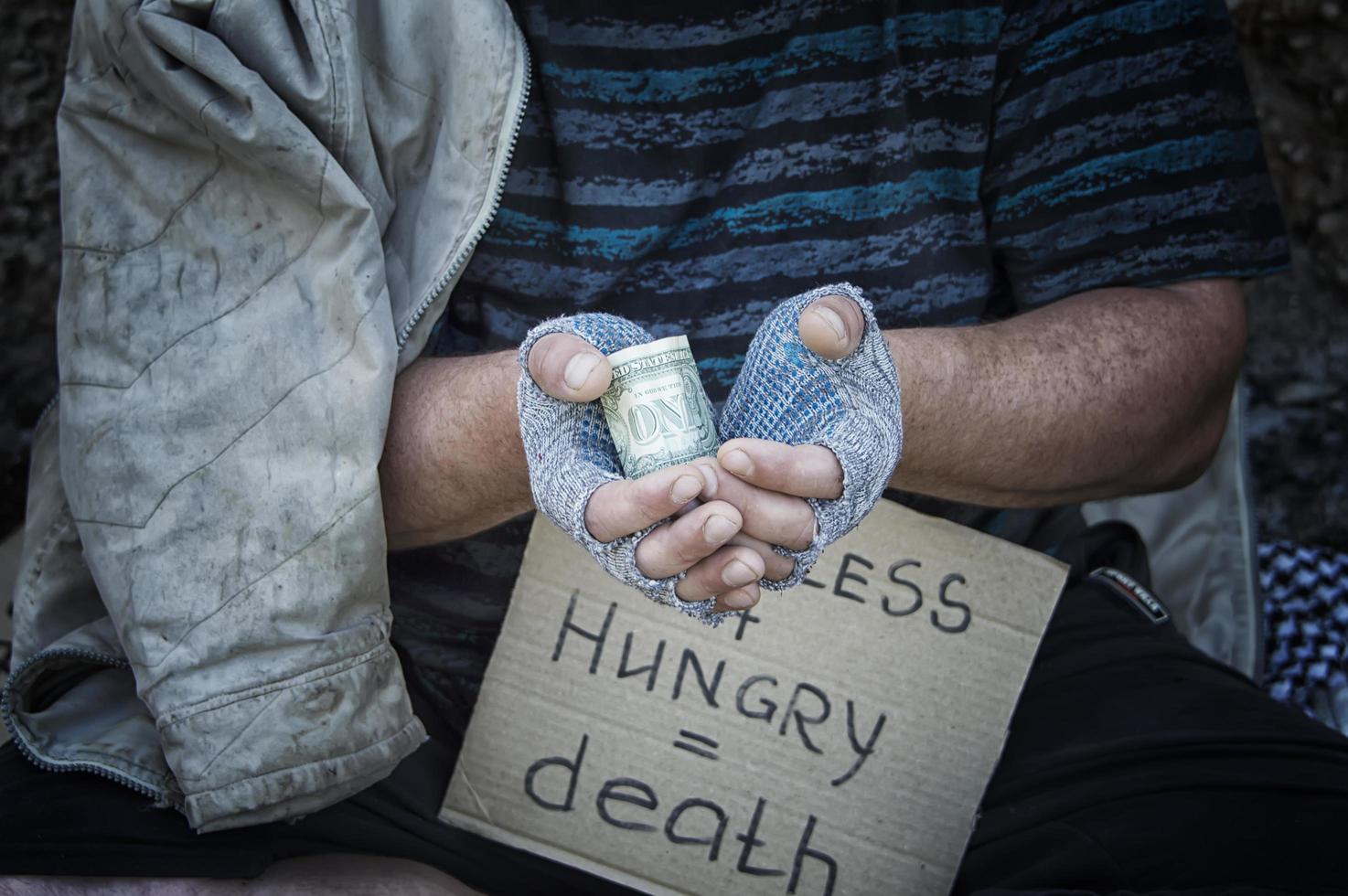um dólar nas mãos de um sem-teto de luvas. pobreza, fome, desemprego. foto