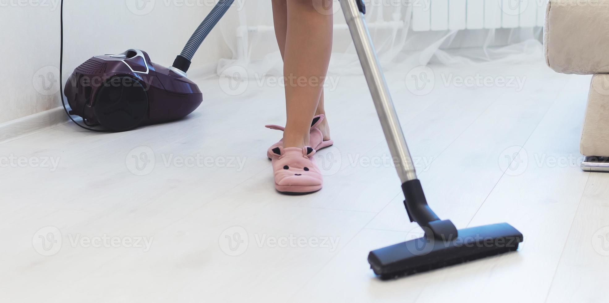 uma garota de chinelos e roupão de banho limpando o chão de um apartamento. foco seletivo. grão de filme. foto