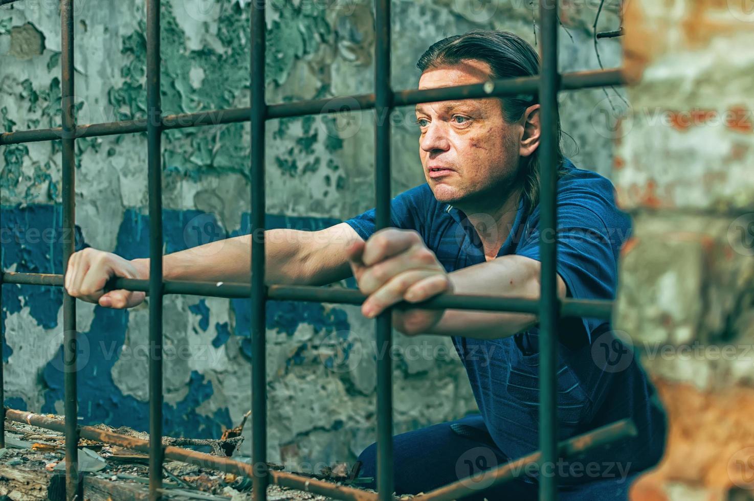 um homem deprimido segura as mãos nas barras da prisão. prisioneiro pelo crime. más condições. grito, desespero, dor, fome. foto