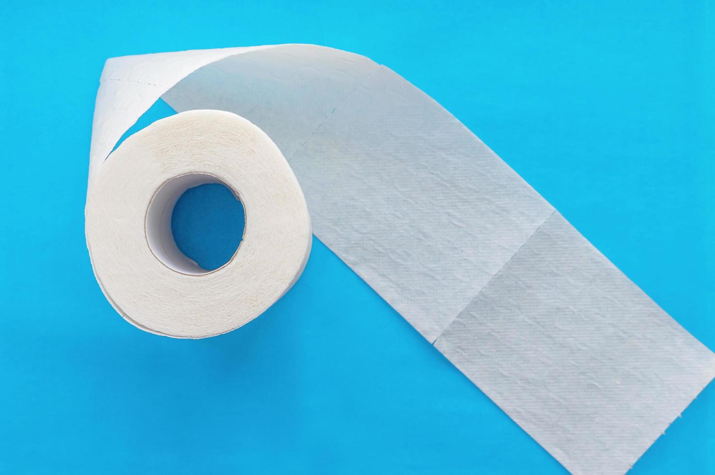 rolo de papel higiênico branco sobre fundo azul. fechar-se. foto