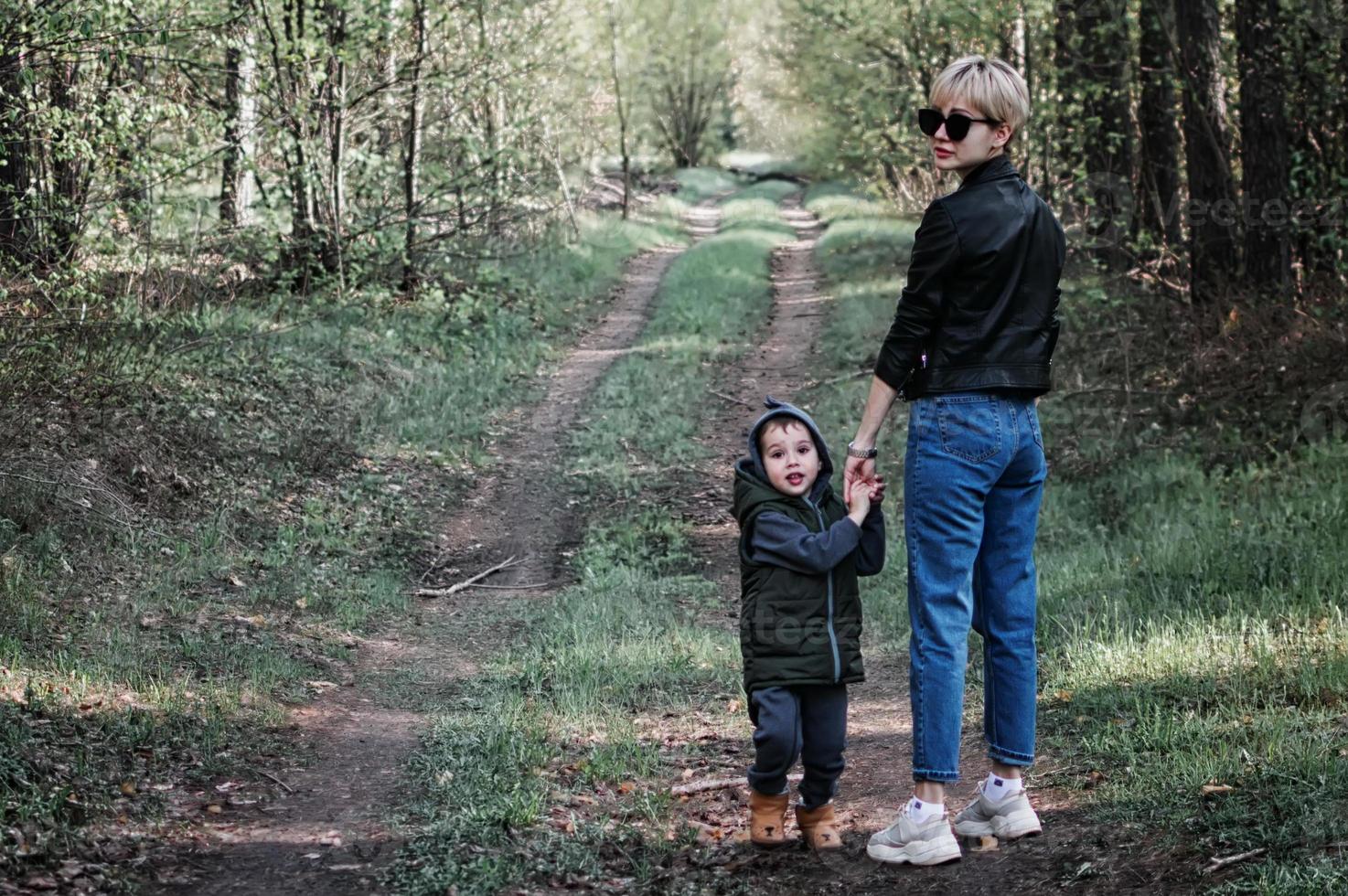 mãe caminha com seu filho na floresta foto