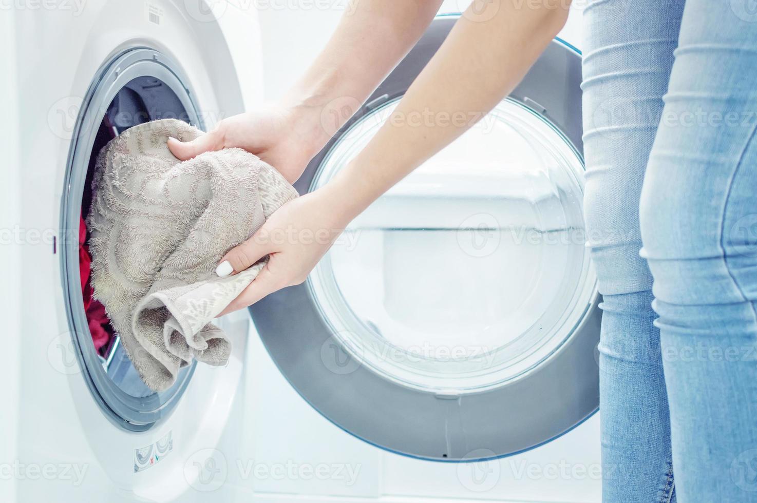 mãos de mulheres colocam roupa na máquina de lavar. empregada. fechar-se. foco seletivo. grão de filme foto