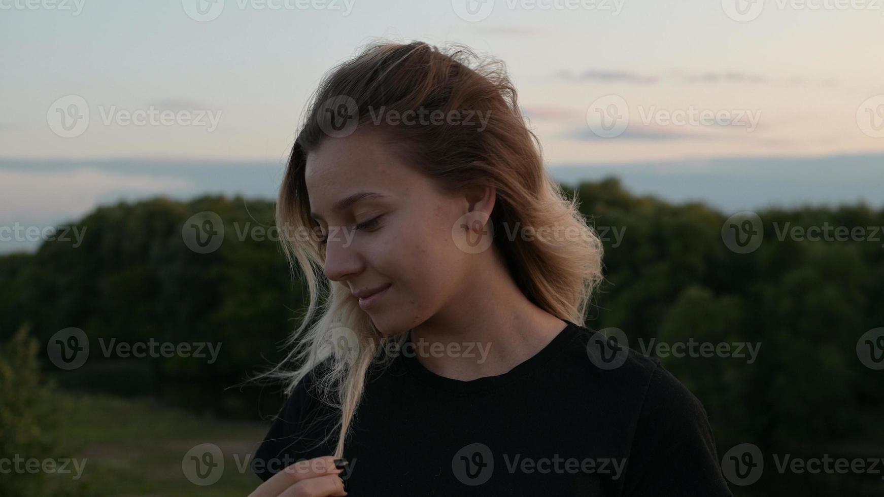 retrato de uma linda menina loira sorridente com os cabelos soltos em pé ao vento no contexto da natureza outono ao pôr do sol conceito de emoções foto