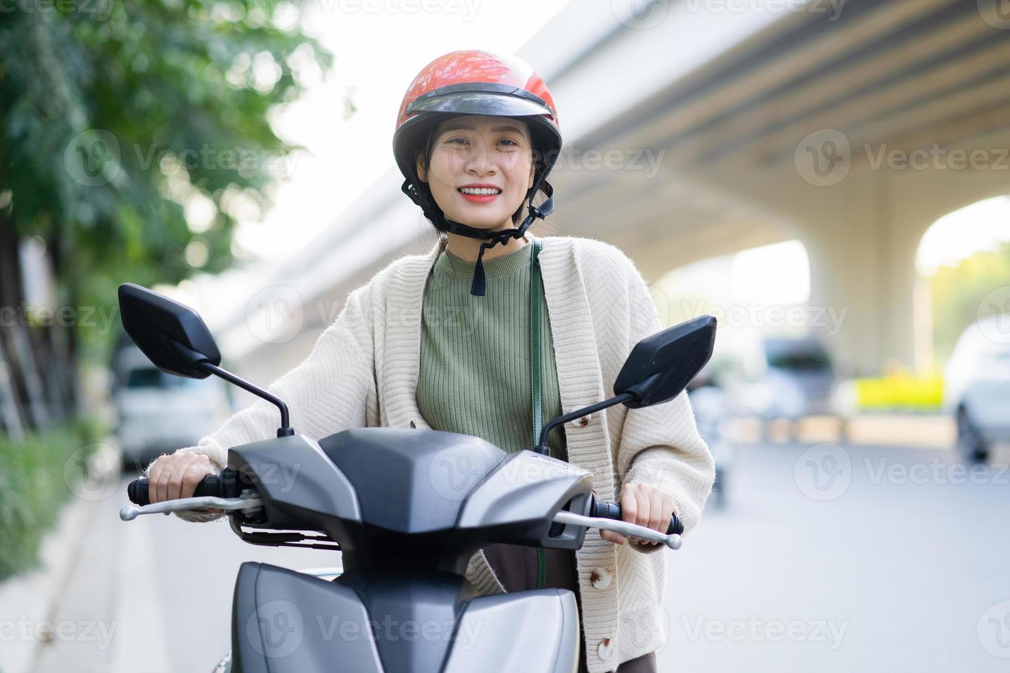 mulher asiática dirigindo uma motocicleta a caminho do trabalho foto