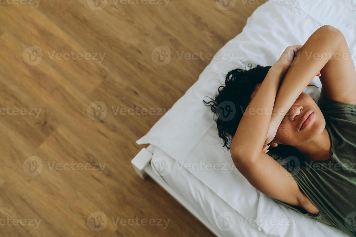 visão aérea de uma mulher africana cobrindo os olhos com a mão na cama foto