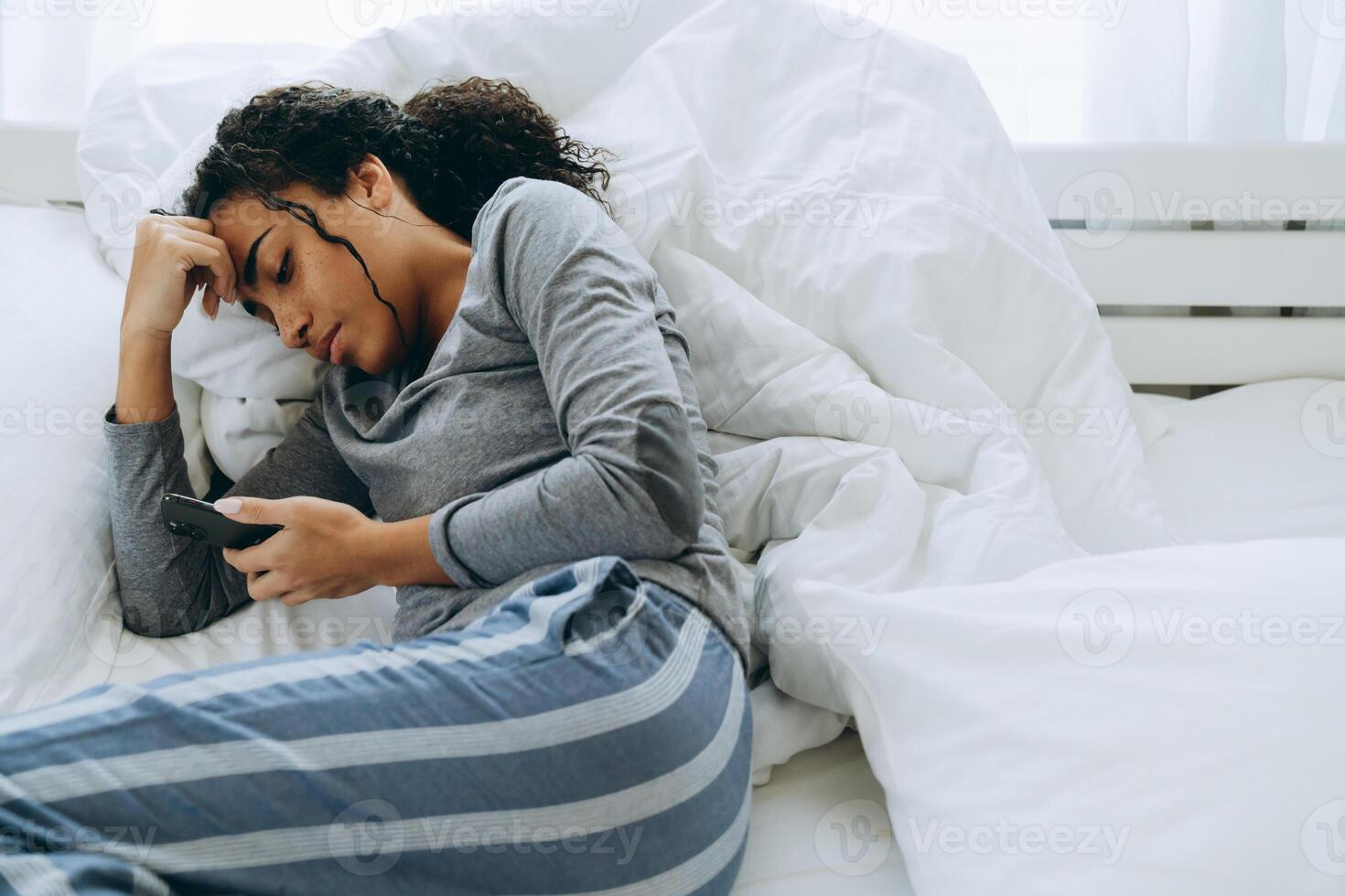 jovem negra usando telefone celular enquanto estava deitada na cama foto