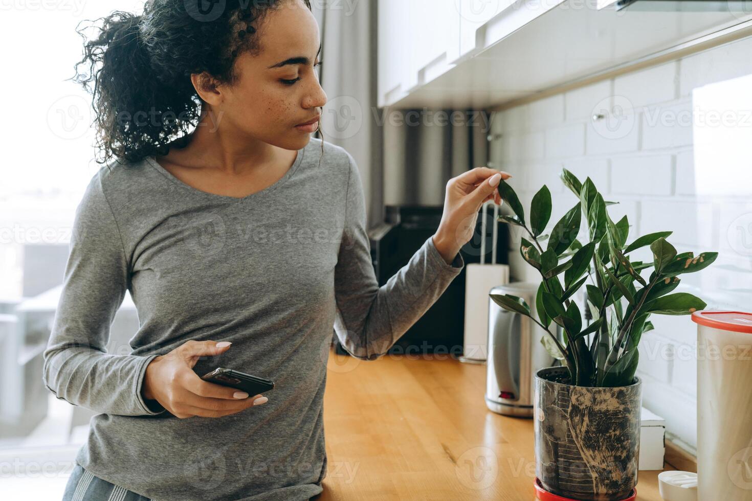 mulher negra usando telefone celular enquanto está na cozinha foto