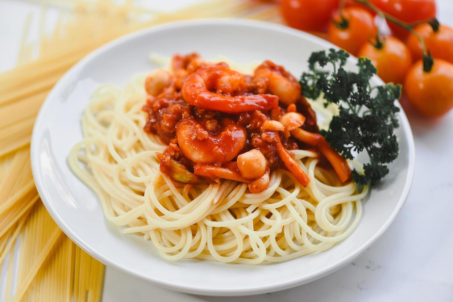 espaguete macarrão italiano à bolonhesa com camarão camarão servido no prato branco com salsa de tomate no restaurante comida italiana e conceito de menu - espaguete frutos do mar vista superior foto