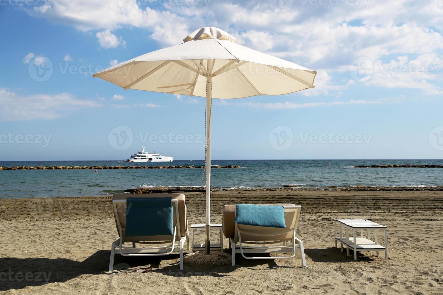 espreguiçadeira elegante na areia amarela para tomar sol na praia foto