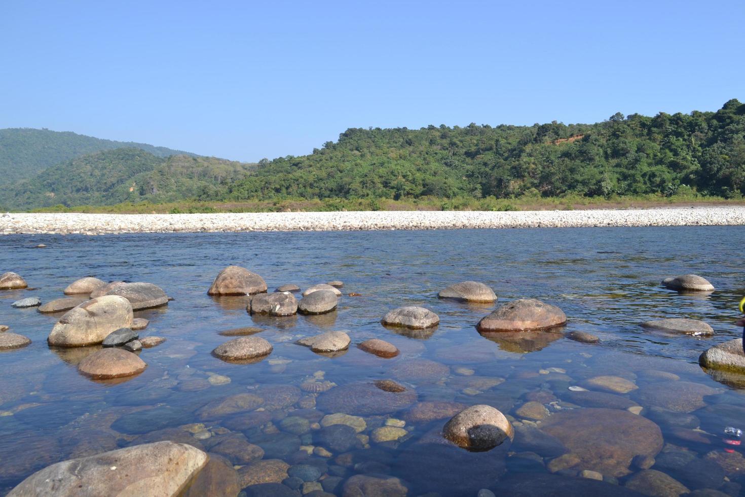 lago calmo e sossegado com uma praia de seixos rodeada de montanhas. foto