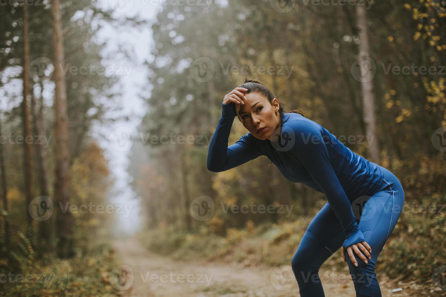 jovem fazendo uma pausa durante exercícios ao ar livre na trilha da floresta no outono foto