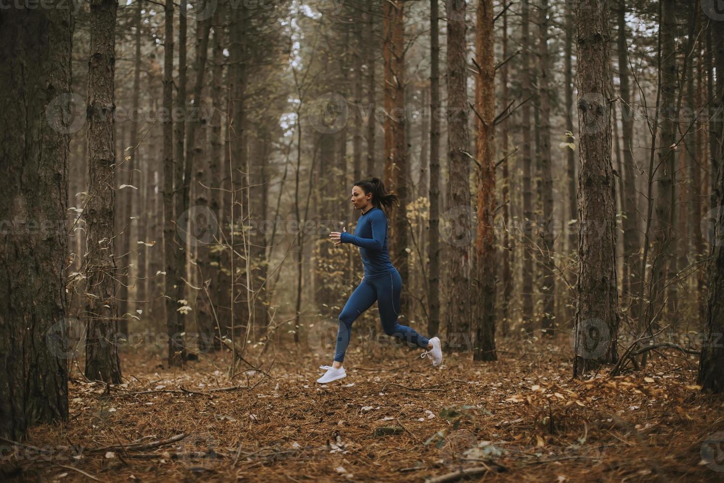 jovem correndo na trilha da floresta no outono foto