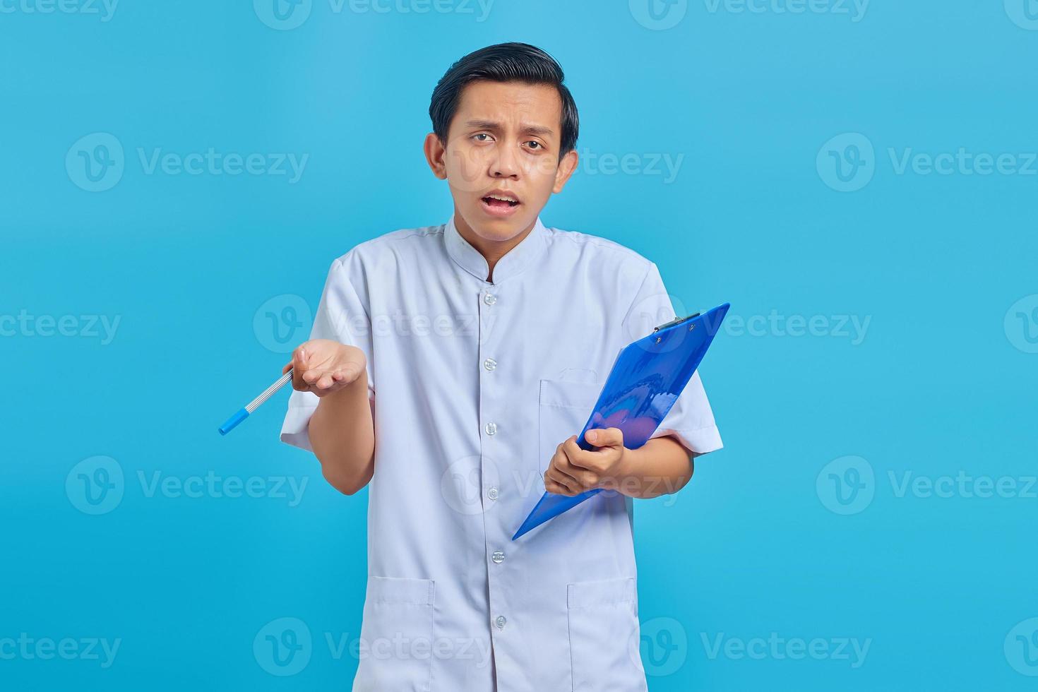 retrato de enfermeiro segurando uma prancheta e uma caneta com cara de surpresa sobre fundo azul foto