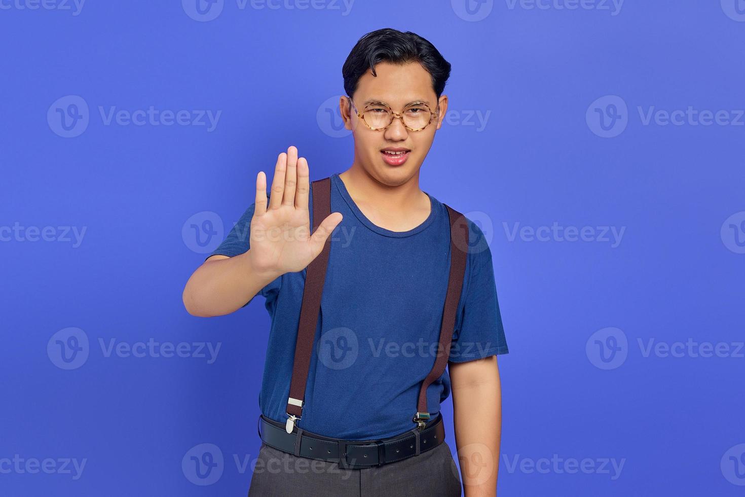 retrato de homem bonito bravo fazendo gesto de parada com as palmas das mãos no fundo roxo foto