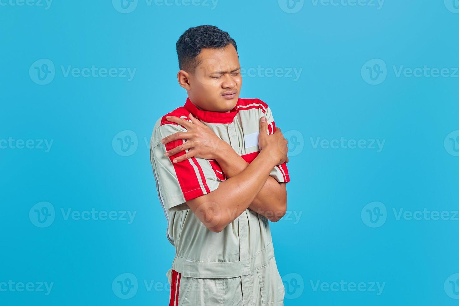 jovem mecânico asiático tremendo sobre fundo azul foto