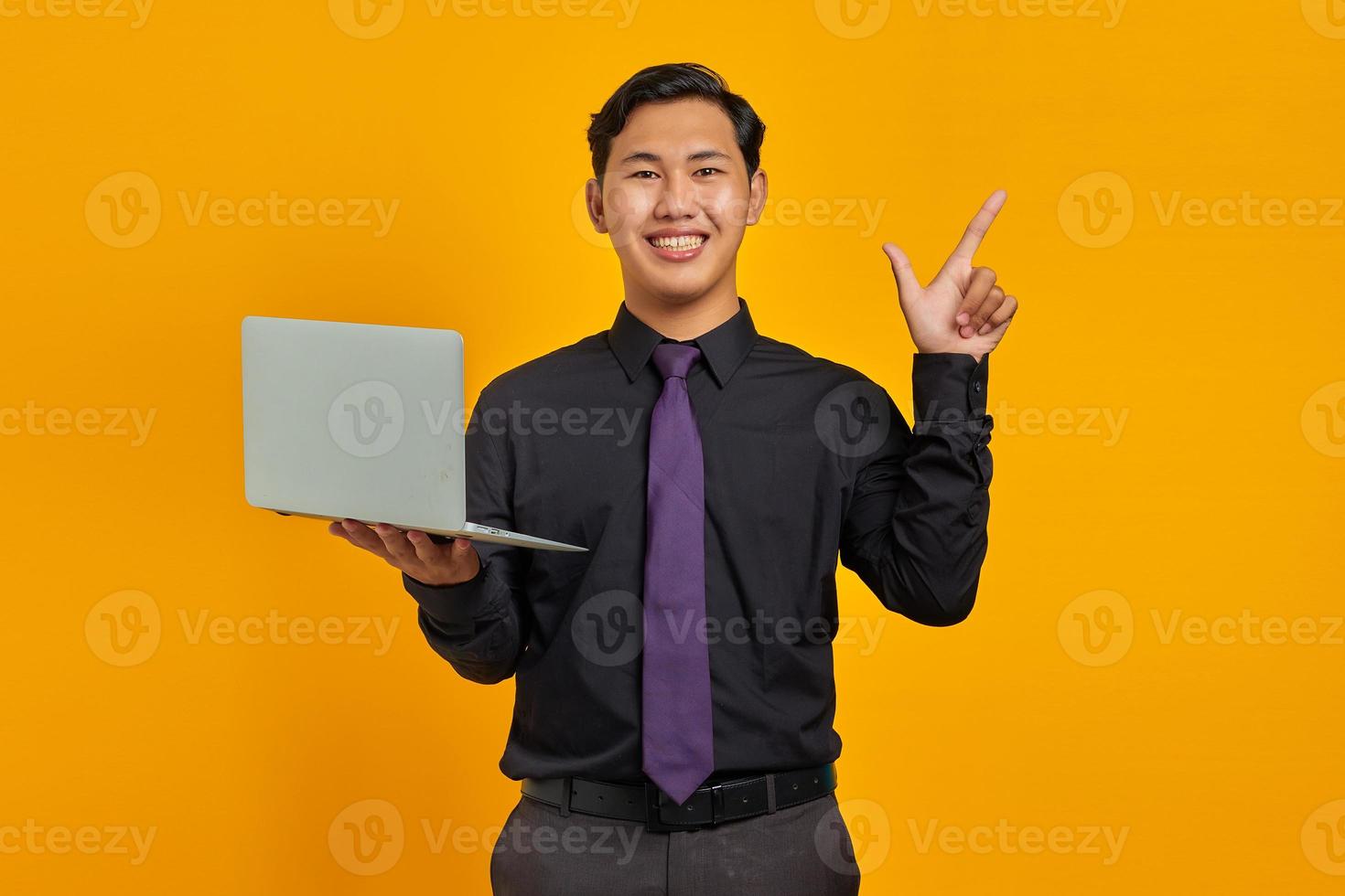 empresário asiático sorridente segurando cartão de crédito apontando o dedo para o espaço da cópia em fundo amarelo foto