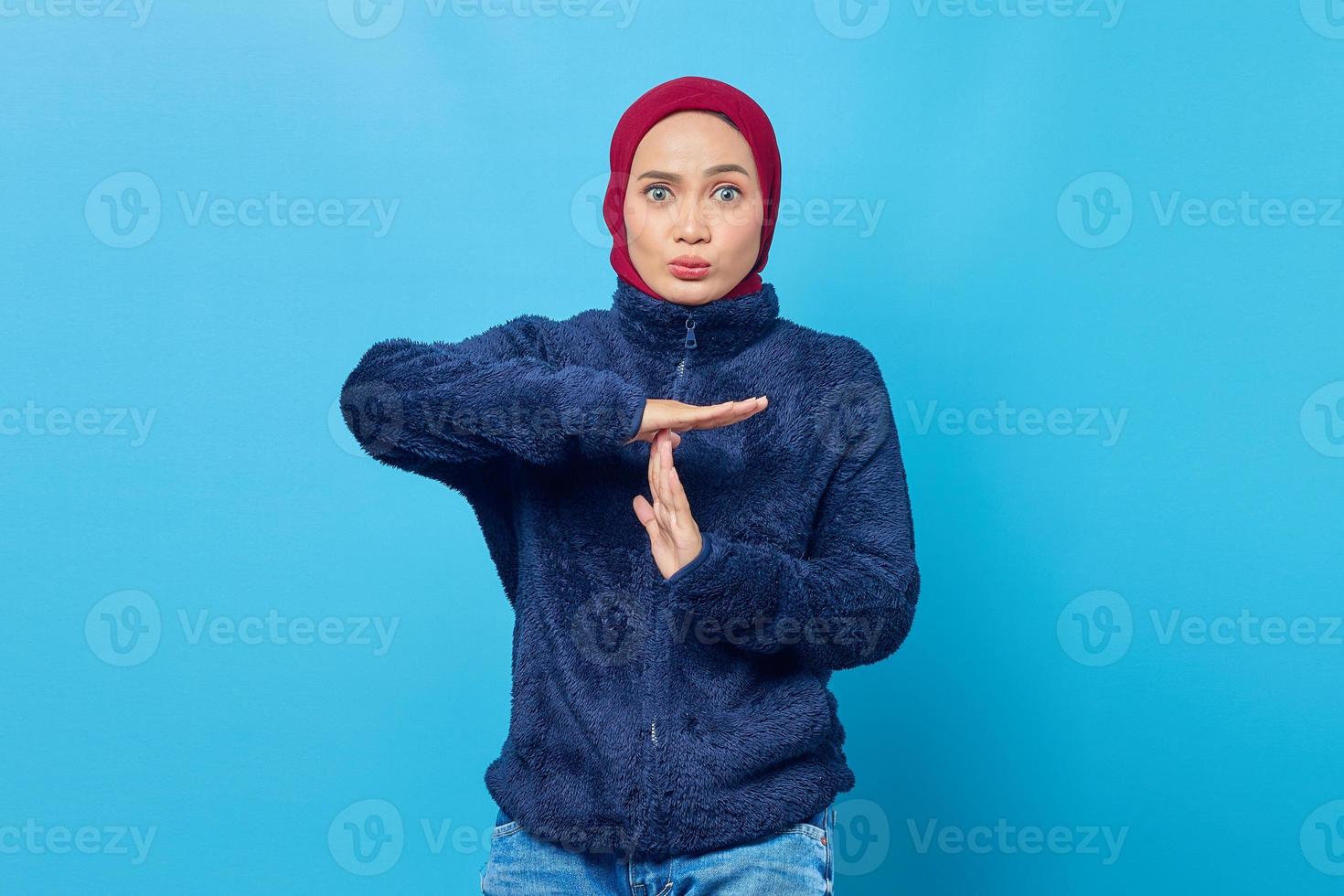 jovem asiática surpresa mostrando gesto de tempo limite em fundo azul foto