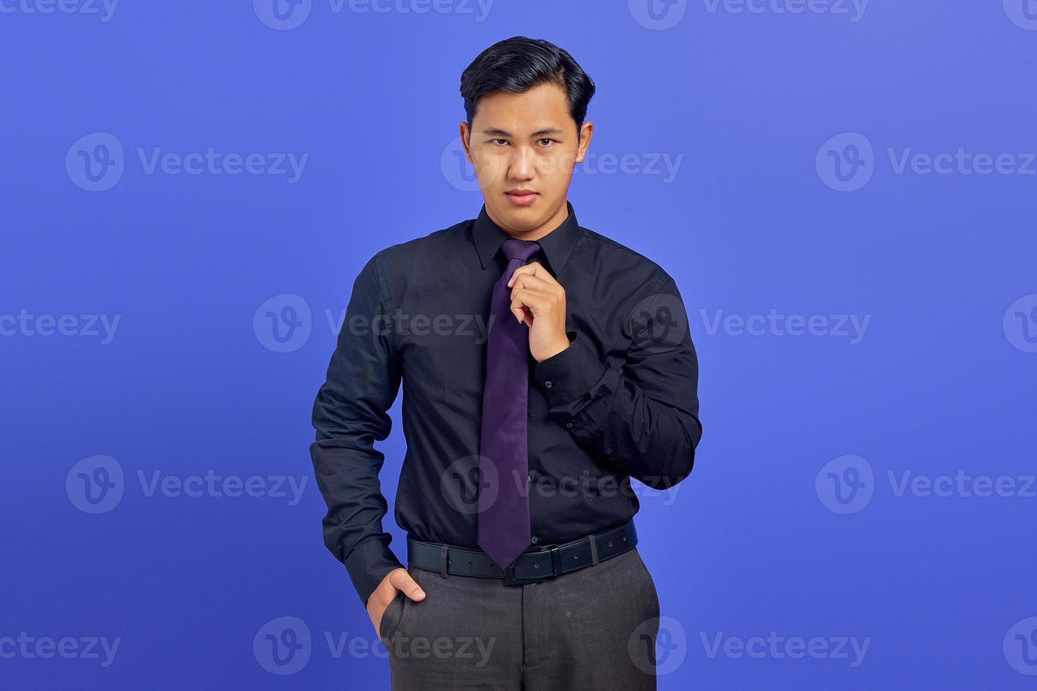 sorridente jovem empresário bonito com um rosto confiante em fundo roxo foto