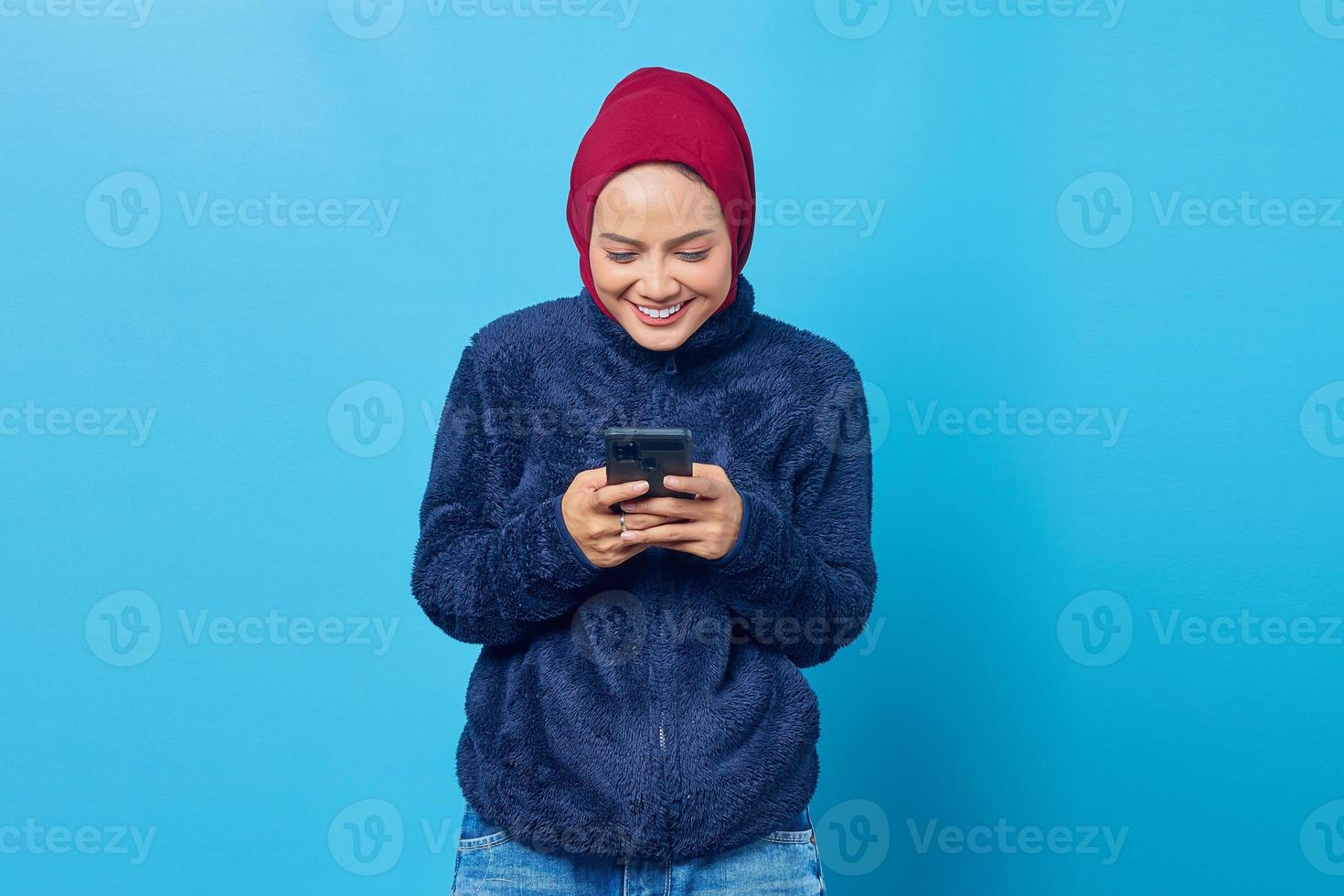 retrato de uma linda mulher asiática sorridente recebendo mensagem de texto do namorado sobre fundo azul foto