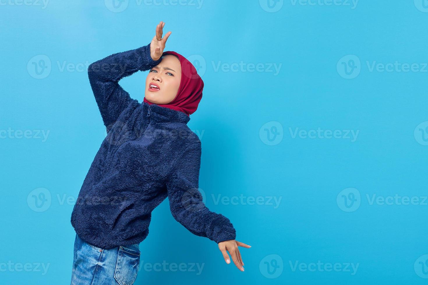 retrato de mulher asiática tocando sua cabeça com uma expressão facial alegre e feliz no fundo azul foto