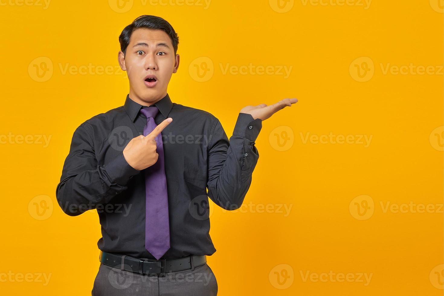 chocado jovem empresário bonito mostrando espaço de cópia na palma da mão sobre fundo amarelo foto