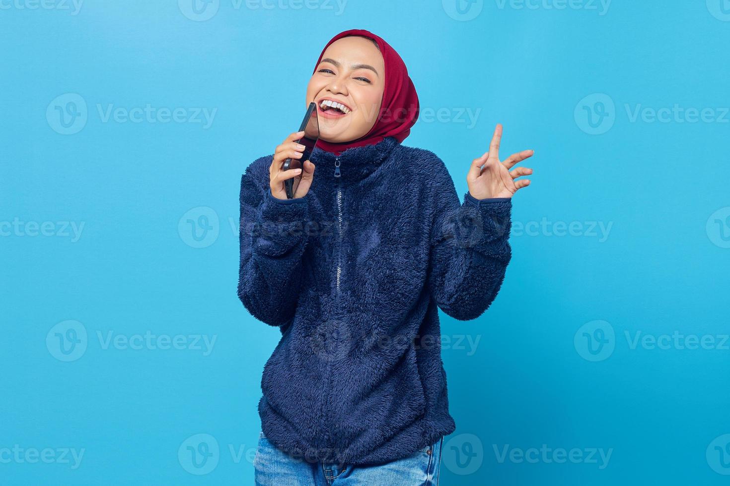 retrato de mulher asiática alegre levantada em movimento de dança e cantando no smartphone foto