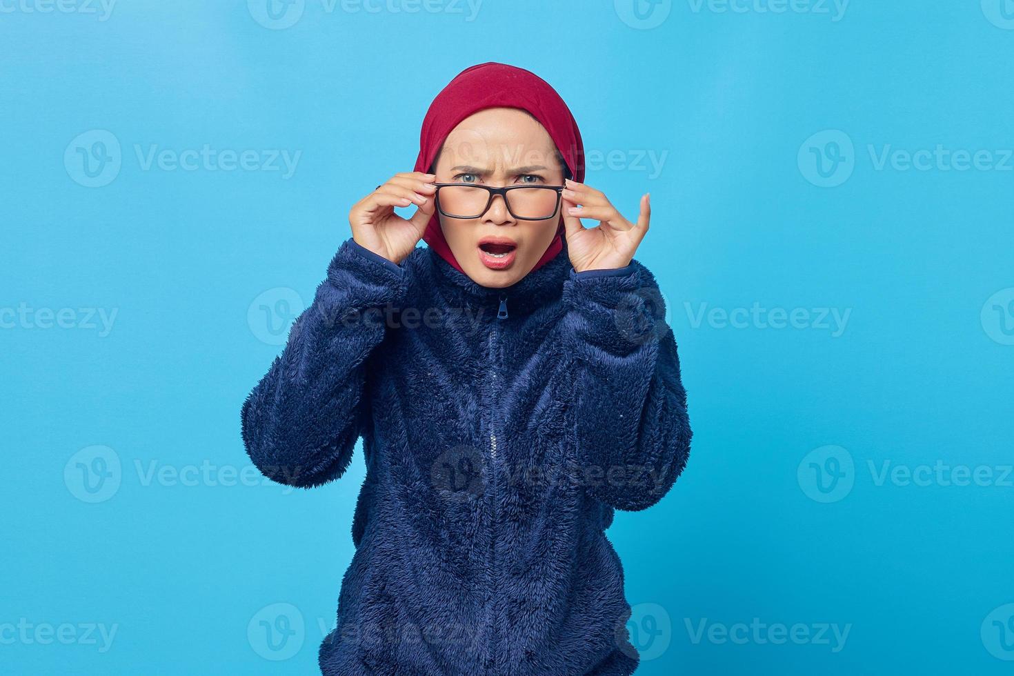 retrato de uma jovem asiática chocada com a boca aberta para ouvir boas notícias sobre fundo azul foto