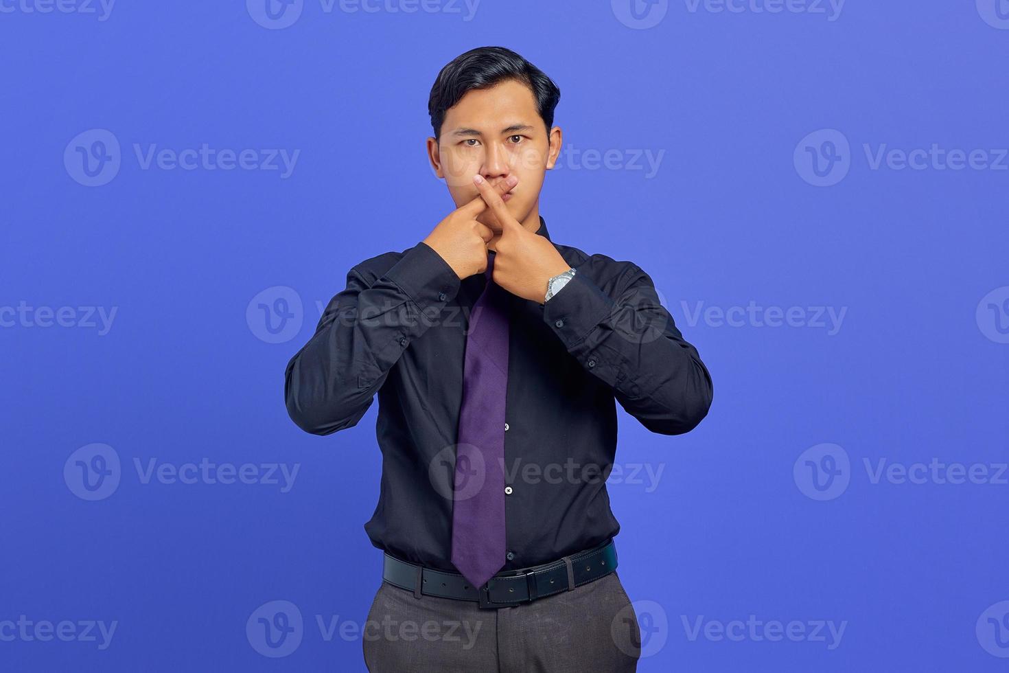 jovem empresário bonito cruzou o dedo e mostrou gesto de recusa no fundo roxo foto