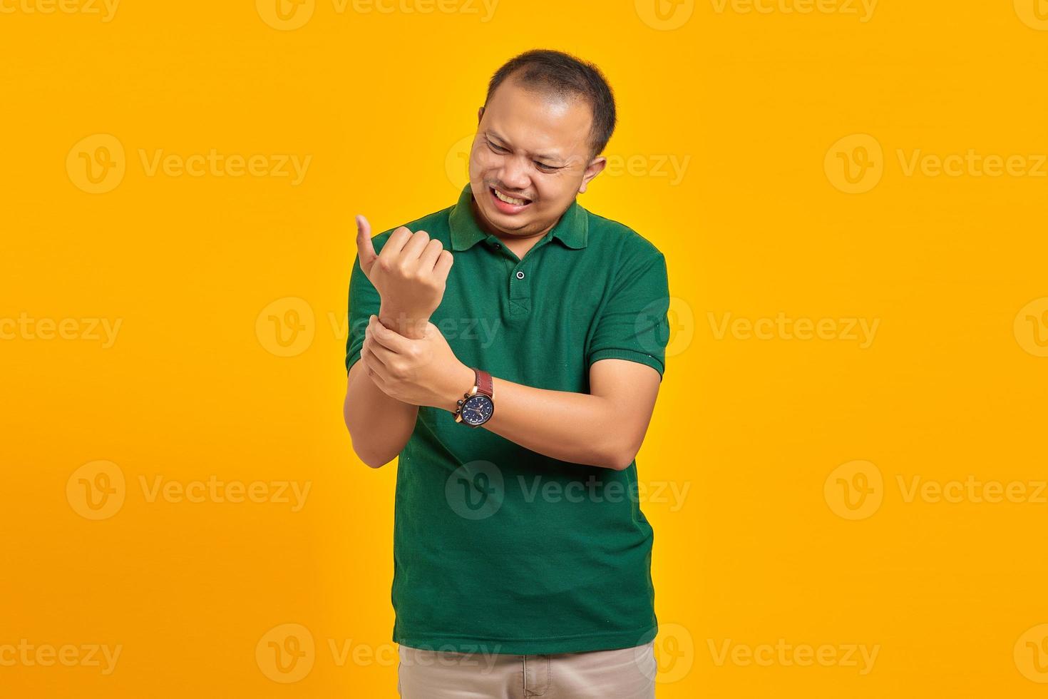 retrato de jovem asiático sofrendo de dor nas mãos e dedos em fundo amarelo foto