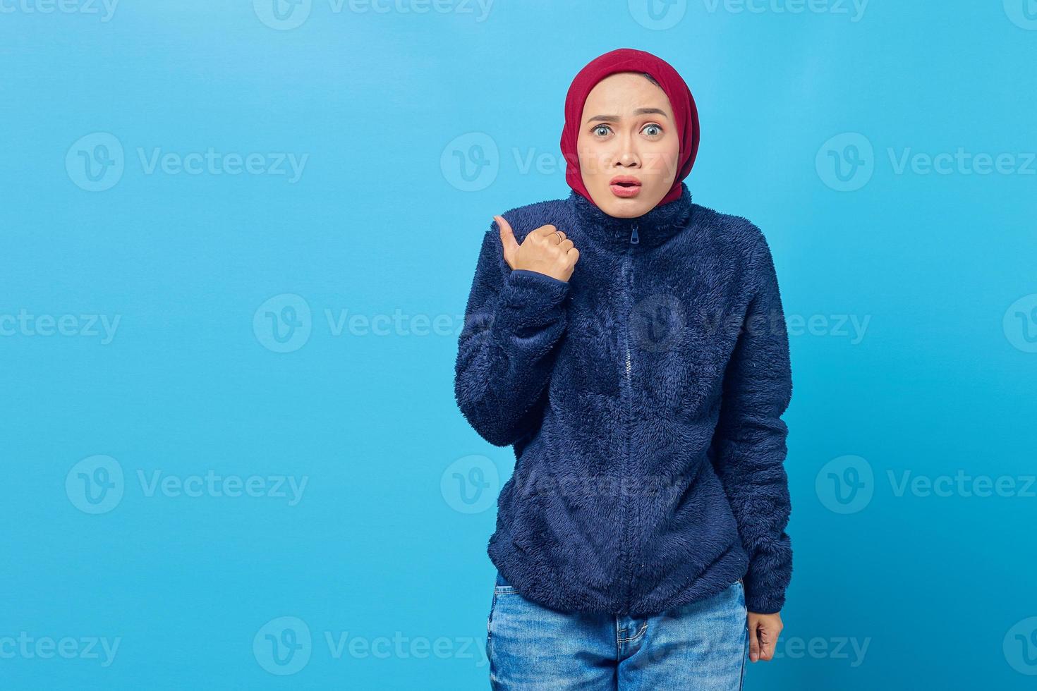 surpreendeu a bela jovem apontando para copiar a sala sobre fundo azul foto