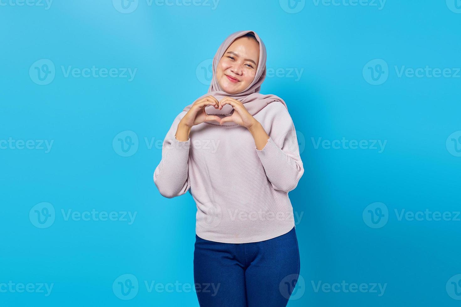 retrato de uma jovem mulher asiática sorridente, mostrando um gesto de formato de coração com as duas mãos. foto