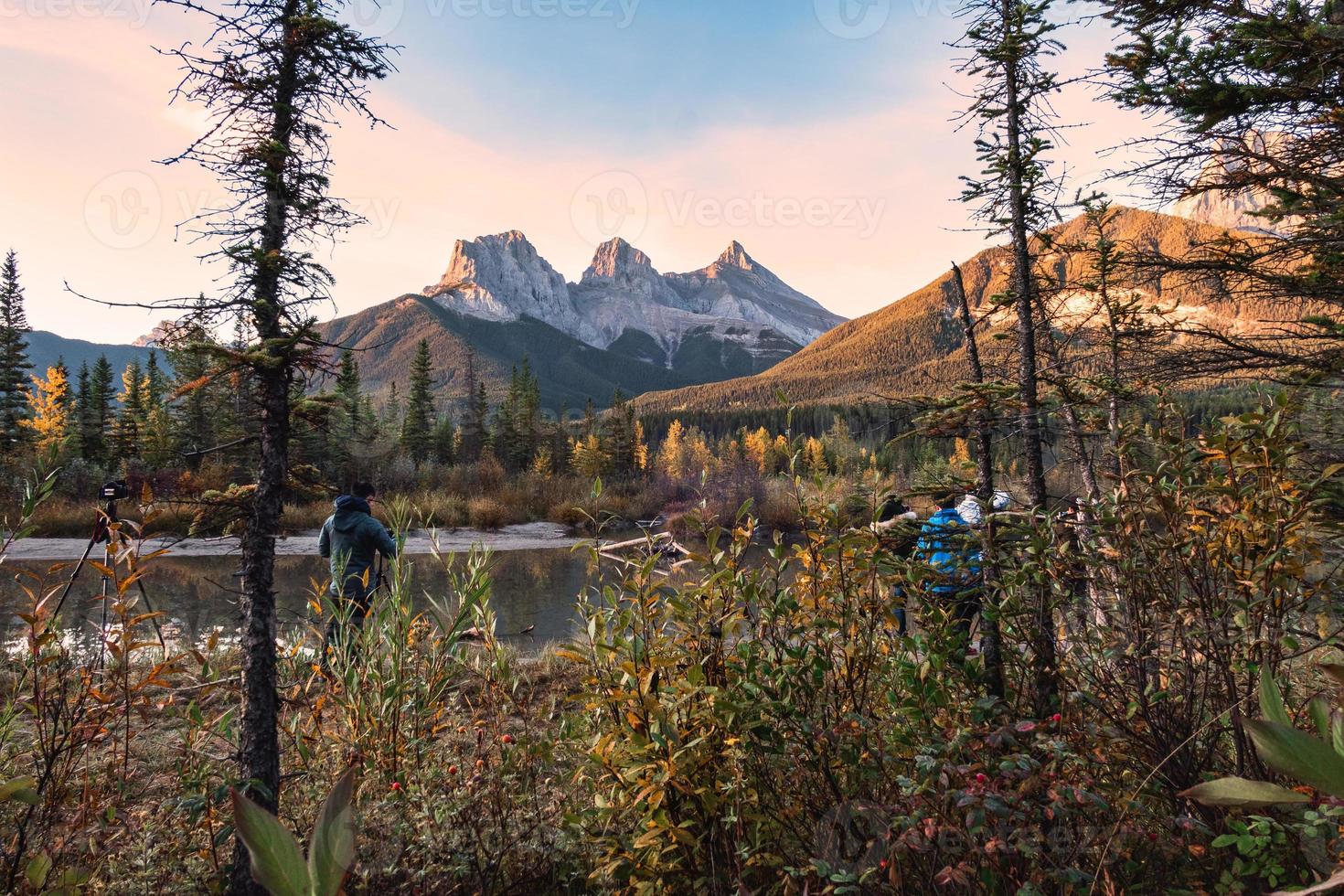 grupo de fotógrafo tirando uma foto em três montanhas irmãs são montanhas rochosas na floresta de outono em canmore, parque nacional de banff