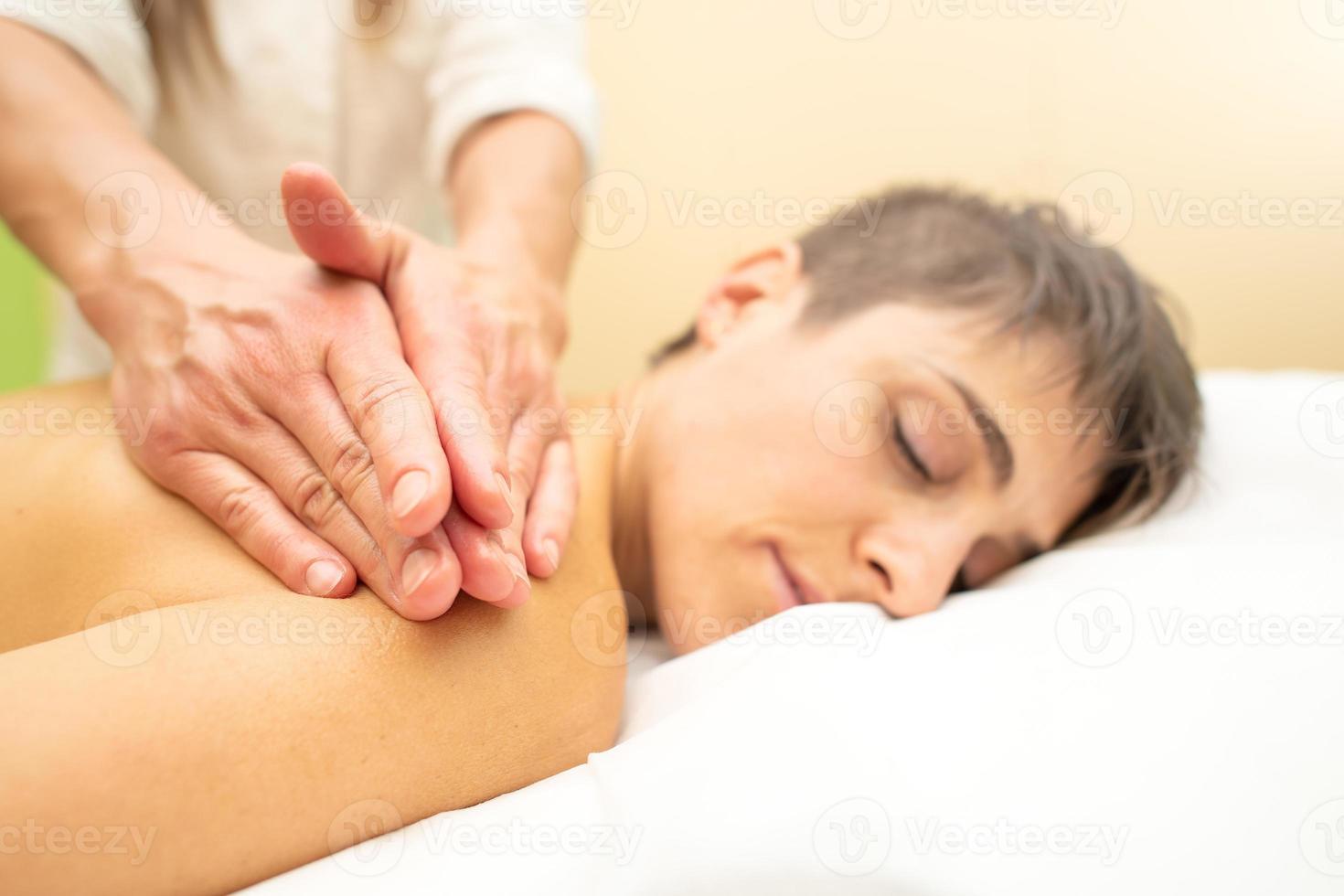 esteticista pratica uma relaxante massagem estética atrás de uma jovem foto