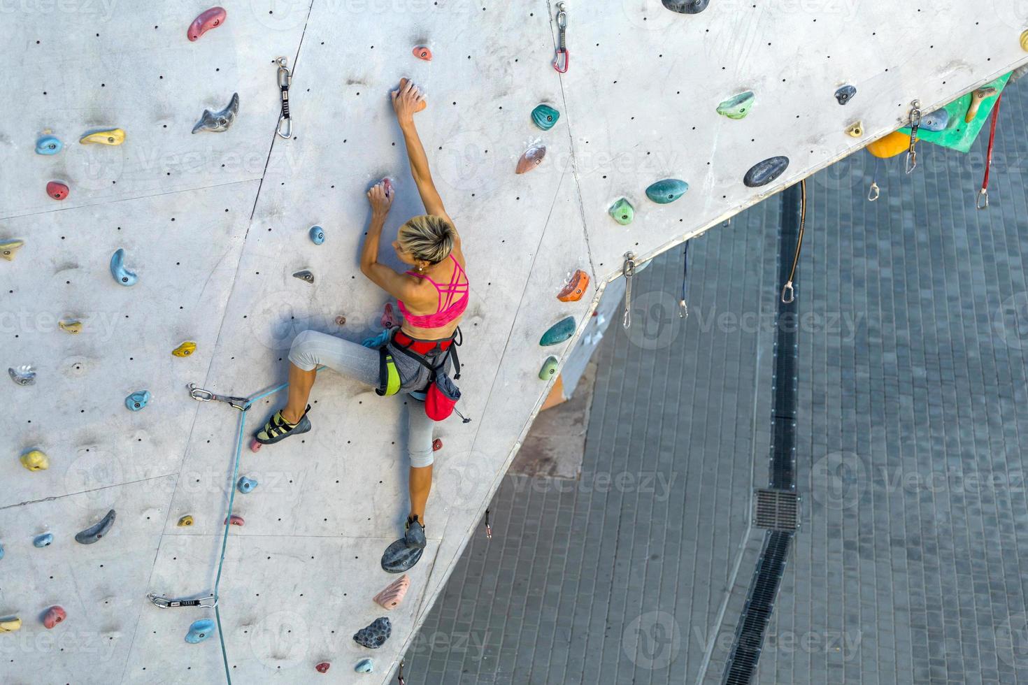 uma mulher está escalando uma parede de escalada foto