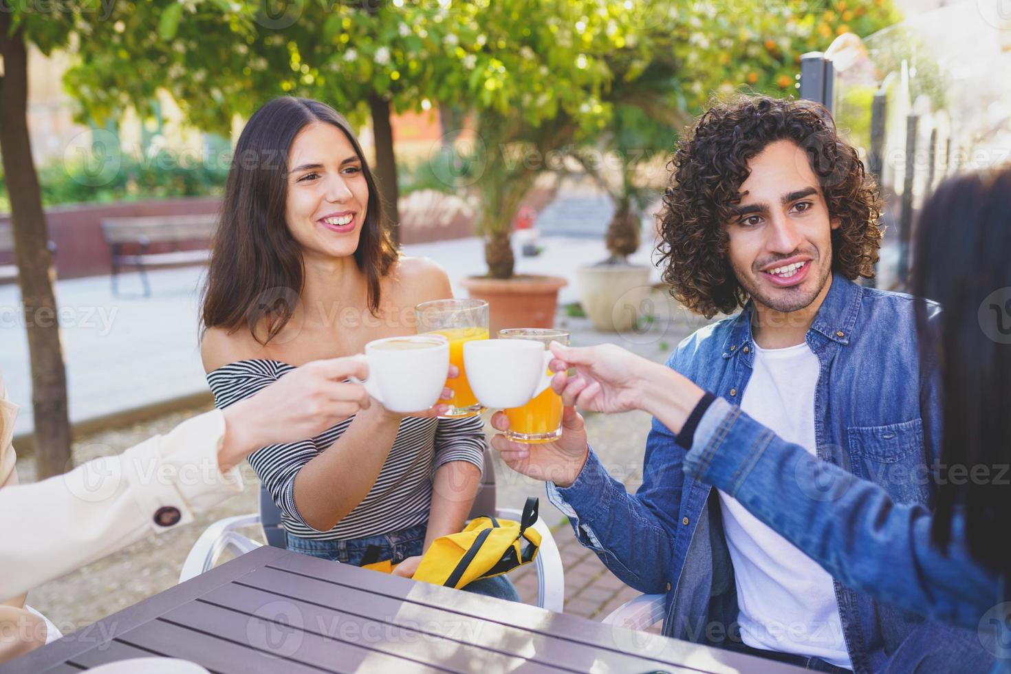 grupo multiétnico de amigos brindando com suas bebidas enquanto tomam uma bebida juntos. foto