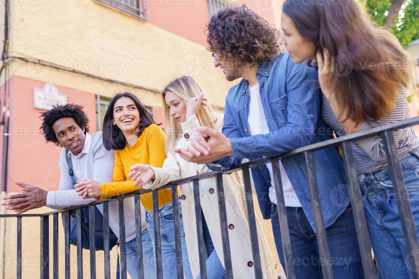 grupo multiétnico de amigos se reuniu na rua encostado em uma grade. foto